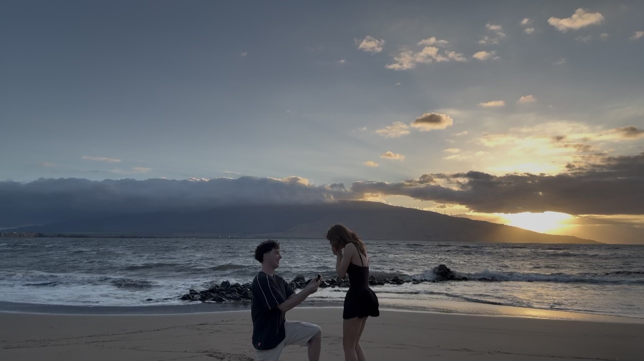 Graysen on one knee proposing to Bailey on a beach at sunset